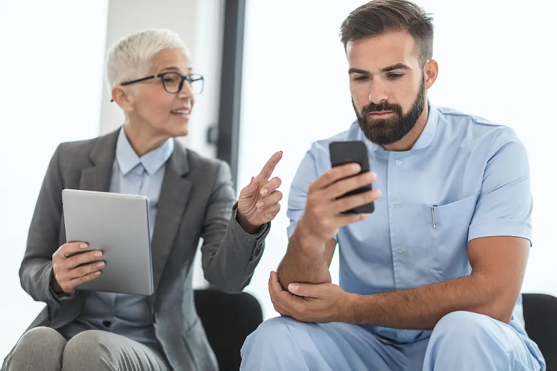 Responsabile e operatore che consultano insieme tablet e telefono